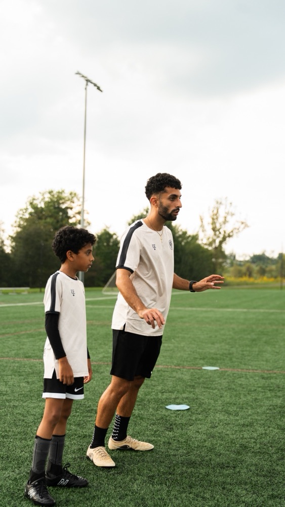A coach gesturing while giving instruction to a player during training