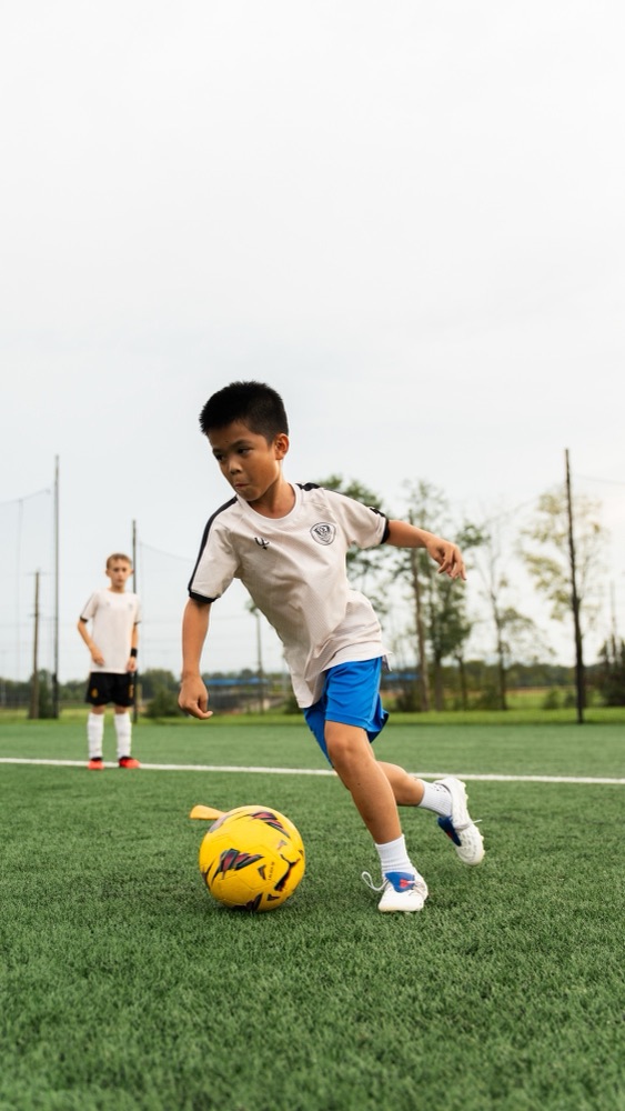 A player dribbling with a teammate watching behind him